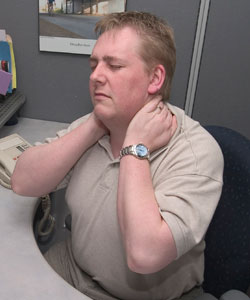 Man sitting at desk holding neck in pain